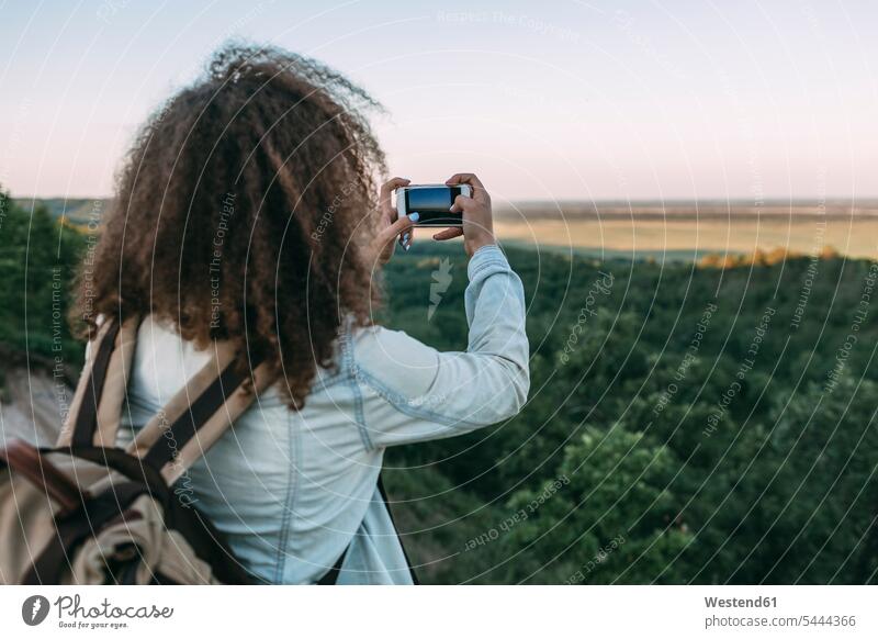 Rückansicht eines Teenagers, der die Landschaft fotografiert Smartphone iPhone Smartphones Teenagerin junges Mädchen Teenagerinnen weiblich junge Frau Handy