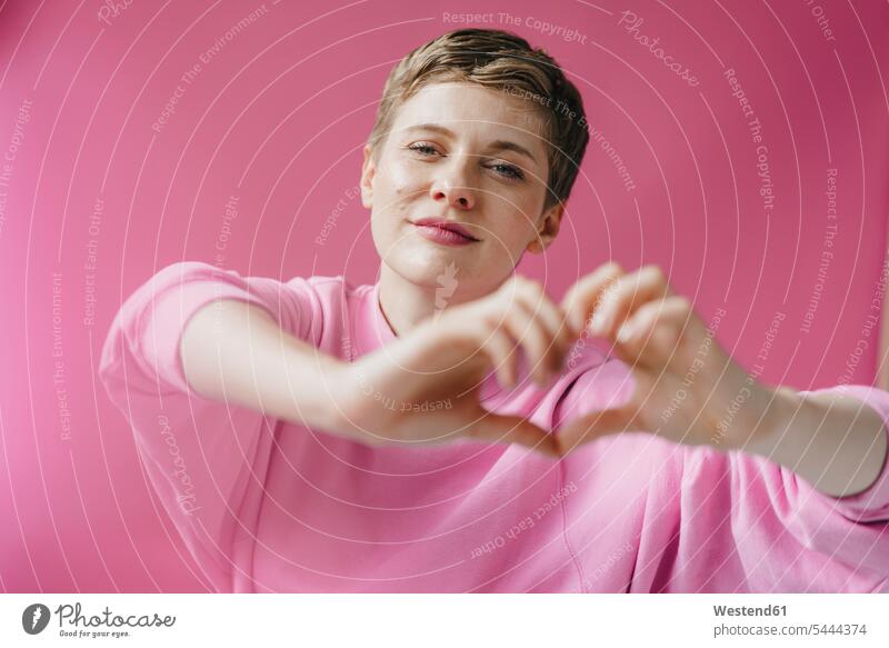 Porträt einer Frau in rosa, das Herz mit ihren Händen formend Portrait Porträts Portraits pink pinkfarben Herzform Herzformen Herzen Hand weiblich Frauen