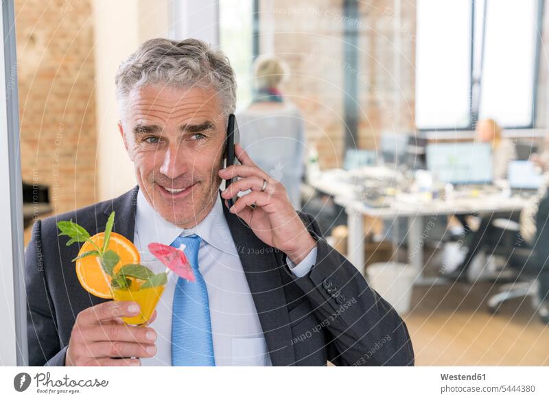 Reifer Geschäftsmann trinkt Cocktail während er telefoniert feiern Cocktails Longdrink Longdrinks Businessmann Businessmänner Geschäftsmänner Büro Office Büros