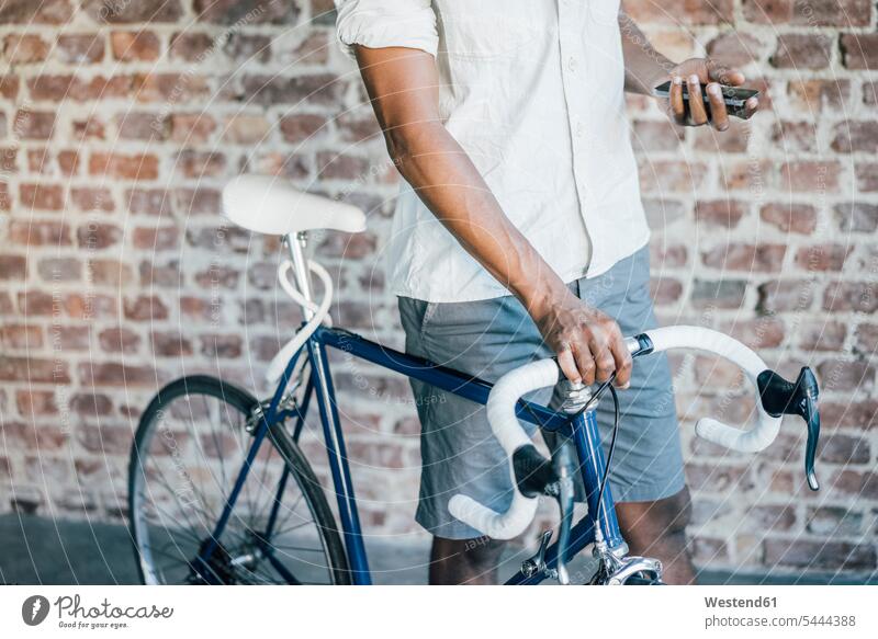 Nahaufnahme eines Mannes mit Fahrrad, der sein Handy überprüft Bikes Fahrräder Räder Rad Männer männlich Mobiltelefon Handies Handys Mobiltelefone Raeder