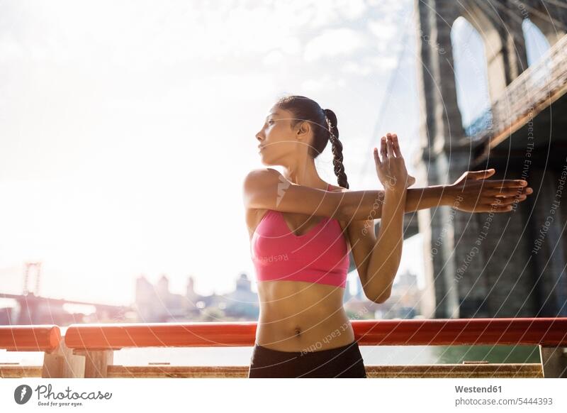 Frau macht morgens Dehnungsübungen in Manhattan in der Nähe der Brooklyn Bridge trainieren Sportlerin Sportlerinnen Brücke Bruecken Brücken Workout aufwärmen