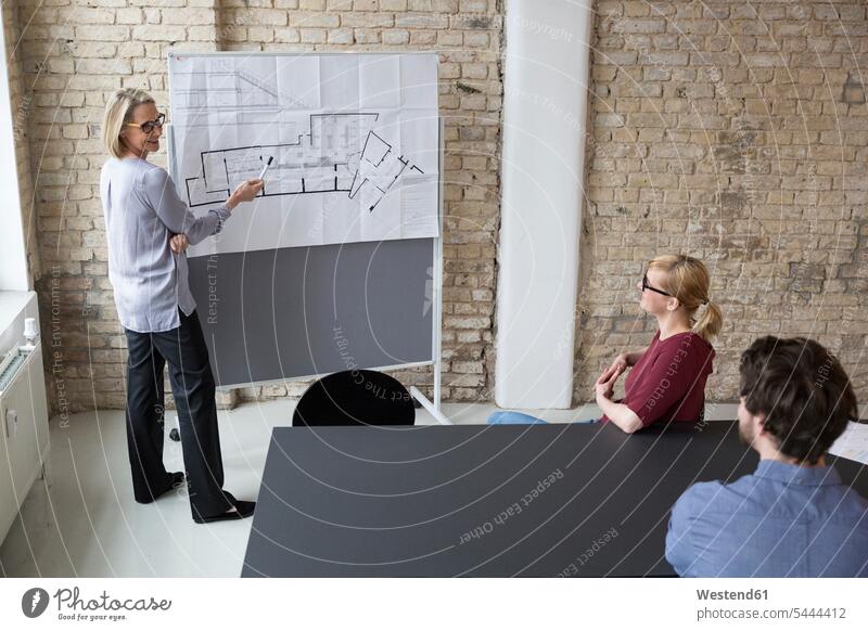 Reife Geschäftsfrau erklärt Kollegen den Grundriss Beratung Geschäftsleute Geschäftspersonen Bauplan Architekturplan Konstruktionsplan Konstruktionszeichnung