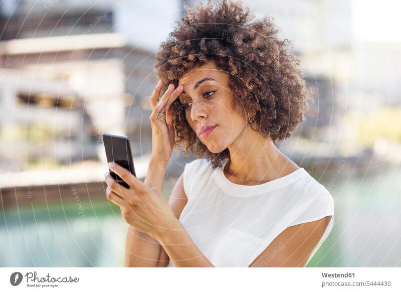 Junge Frau bereitet sich auf ein Selfie vor und überprüft ihr Make-up Handy Mobiltelefon Handies Handys Mobiltelefone checken Selfies Make up Schminke Locken