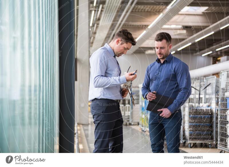 Zwei Männer in Fabrikhalle untersuchen Produkt Fabriken Mann männlich Kollegen Arbeitskollegen arbeiten Erwachsener erwachsen Mensch Menschen Leute People