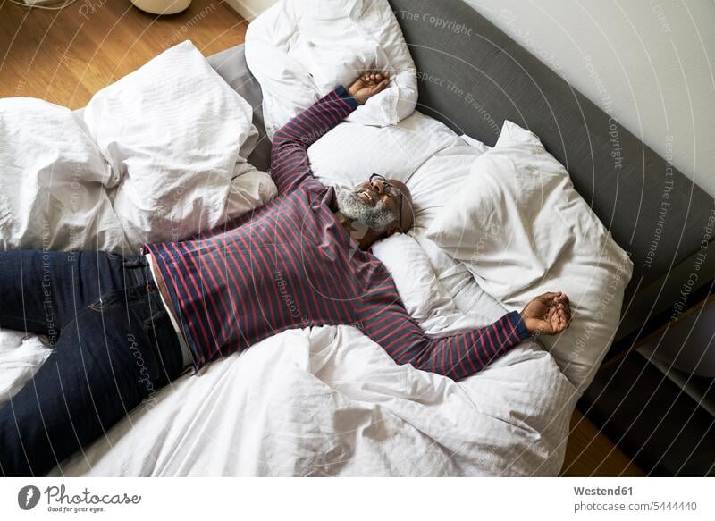 Reifer Mann liegt auf dem Bett und lächelt Betten Zuhause zu Hause daheim Männer männlich entspannt entspanntheit relaxt tagträumen Tagtraum liegen liegend