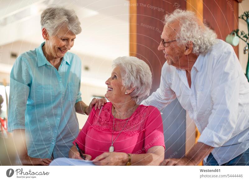 Ältere Frau unterzeichnet einen Vertrag, Freunde beruhigen sie Freundschaft Kameradschaft Altersheim Altenheim Seniorenheim Formular Formulare ausfüllen