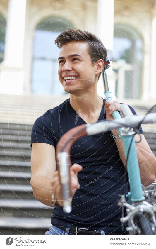 Porträt eines glücklichen jungen Mannes mit Rennrad auf der Schulter Portrait Porträts Portraits Rennräder Männer männlich Fahrrad Bikes Fahrräder Räder Rad