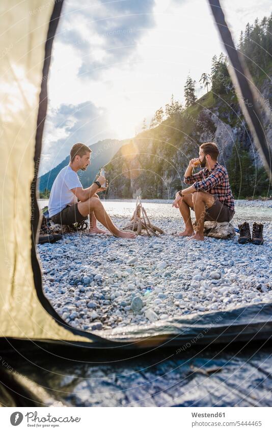 Deutschland, Bayern, zwei Wanderer, die abends auf einer Kiesbank zelten Freunde Freundschaft Kameradschaft Trekking Trecking Camping Campen Zelt Zelte sitzen