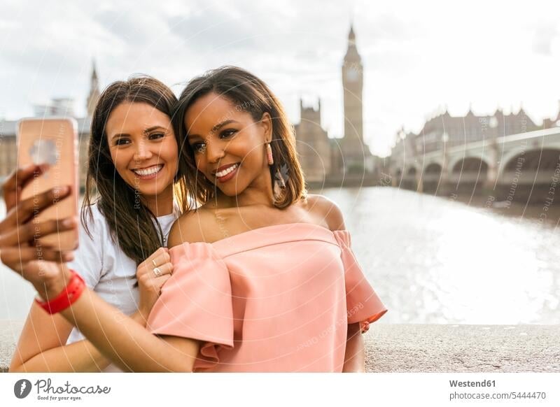 UK, London, zwei schöne Frauen machen ein Selfie in der Nähe der Westminster Bridge Selfies Handy Mobiltelefon Handies Handys Mobiltelefone lächeln weiblich