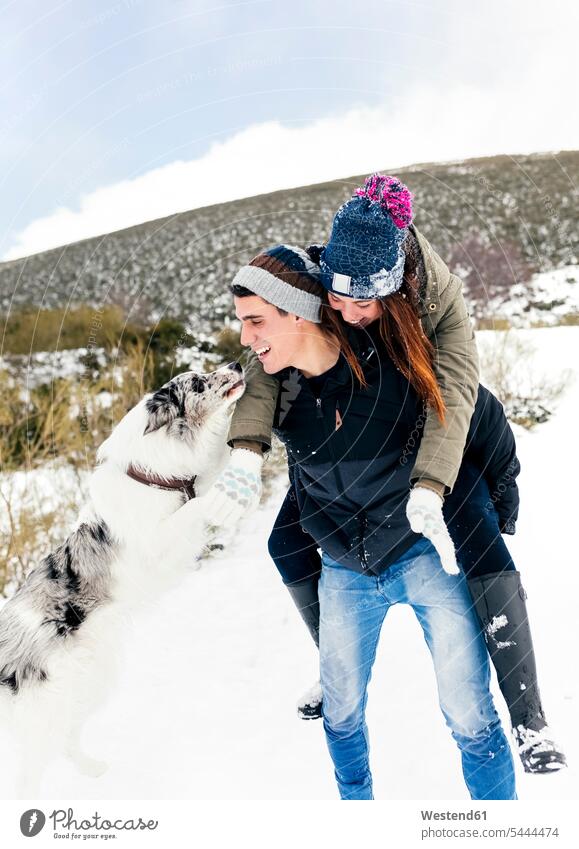 Junger Mann trägt sein Mädchen im Winter huckepack gebraten Schnee Hund Hunde Freundschaft Freunde Kameradschaft Paar Pärchen Paare Partnerschaft tragen