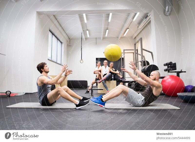 Zwei Athleten trainieren mit dem Ball in der Turnhalle unter Beobachtung der Trainingspartner Fitnessstudio Fitnessclubs Fitnessstudios Bälle werfen Wurf fit