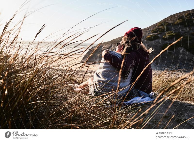 Portugal, Algarve, Ehepaar sitzt bei Sonnenuntergang am Strand Beach Straende Strände Beaches glücklich Glück glücklich sein glücklichsein Paar Pärchen Paare