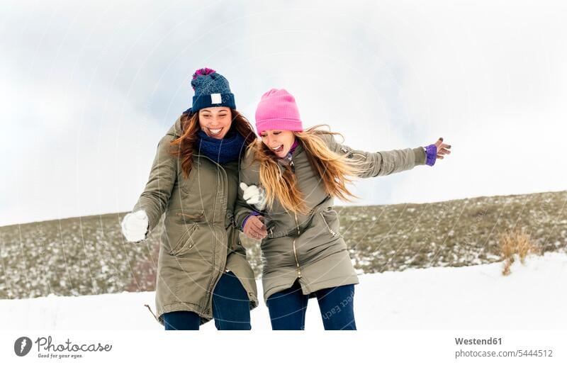 Zwei Freunde amüsieren sich im Schnee Freundinnen lachen Winter winterlich Winterzeit Freundschaft Kameradschaft Wetter positiv Emotion Gefühl Empfindung