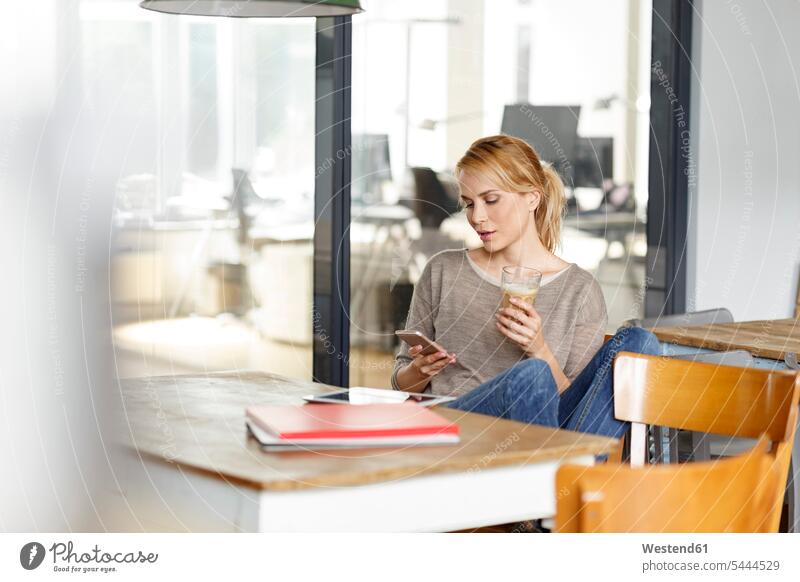 Frau überprüft Mobiltelefon im Büro Handy Handies Handys Mobiltelefone Office Büros weiblich Frauen Telefon telefonieren Kommunikation Telekommunikation