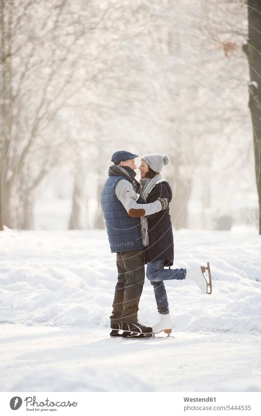 Älteres Paar umarmt sich auf gefrorenem See Schlittschuhläufer Schlittschuhlaeufer eislaufen schlittschuhlaufen lächeln Spaß Spass Späße spassig Spässe spaßig