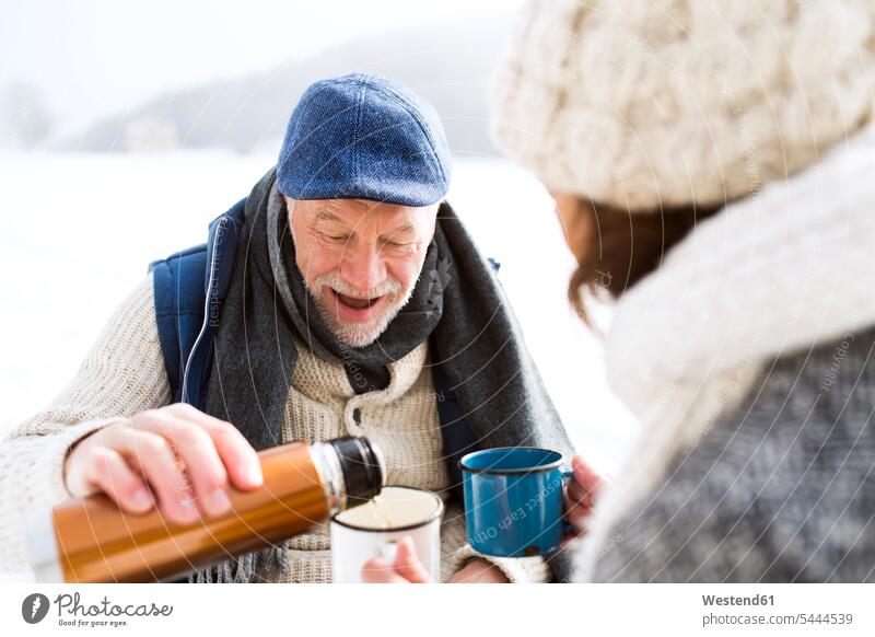 Älteres Ehepaar macht eine Pause mit heissen Getränken im Schnee Seniorenpaar älteres Paar Seniorenpaare ältere Paare Seniorenpärchen Erwachsenes Paar