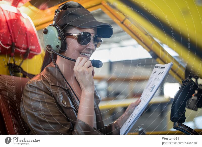 Weibliche Pilotin inspiziert Leichtflugzeug-Cockpit inspizieren prüfen sitzen sitzend sitzt überprüfen testen checken Pilotinnen Flugzeug Flieger Flugzeuge