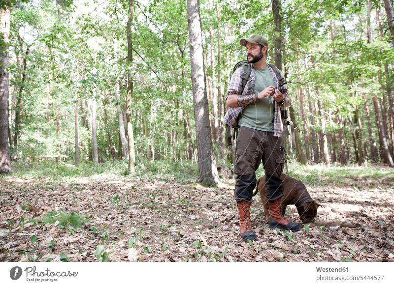 Mann mit Hund auf einer Wanderung im Wald mit dem Handy Hunde Forst Wälder wandern Männer männlich Mobiltelefon Handies Handys Mobiltelefone Haustier Haustiere