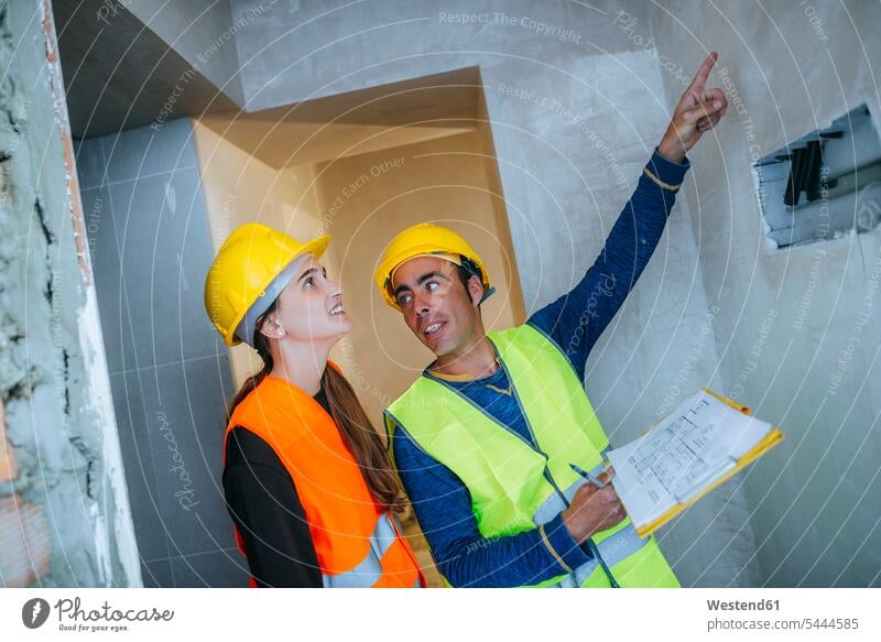 Bauarbeiter zeigt Frau Elektroinstallation Bauplan Architekturplan Bauzeichnung zeigen mit dem Finger zeigen deuten besprechen diskutieren Besprechung Baustelle