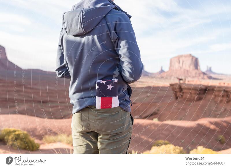 USA, Utah, Rückenansicht eines jungen Mannes mit gefalteter amerikanischer Flagge in der Tasche im Monument Valley Nationalflagge Nationalflaggen Nationalfahnen