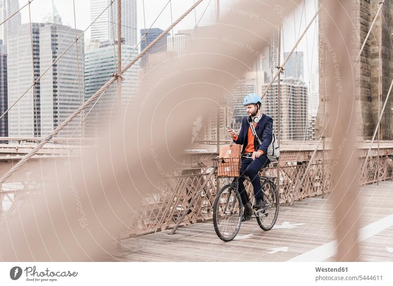 USA, New York City, Mann auf dem Fahrrad auf der Brooklyn Bridge mit Mobiltelefon Männer männlich Brücke Bruecken Brücken Bikes Fahrräder Räder Rad Handy