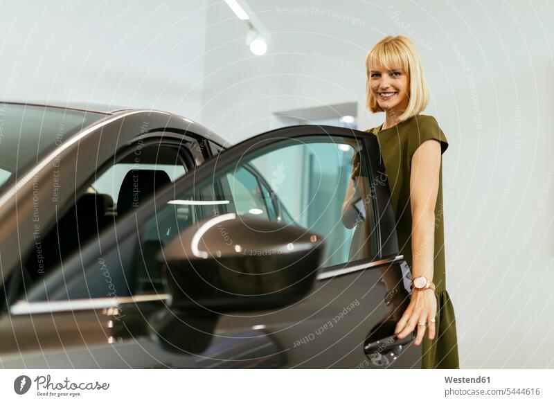 Blonde Frau wählt neues Auto im Autohaus Kundin weiblich Frauen Wagen PKWs Automobil Autos aussuchen auswählen Autohäuser Autohaeuser Autohandlung