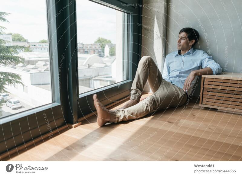 Mann sitzt auf dem Boden und schaut aus dem Fenster Männer männlich Erwachsener erwachsen Mensch Menschen Leute People Personen Loft Lofts Entspannung entspannt