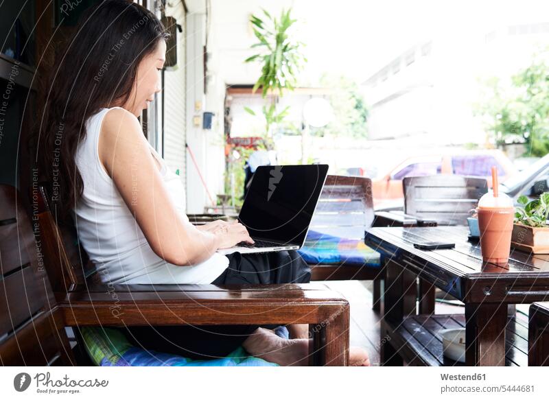 Frau mit Laptop auf Terrassenbank sitzend Bank Sitzbänke Bänke Sitzbank benutzen Notebook Laptops Notebooks weiblich Frauen sitzt Computer Rechner Erwachsener