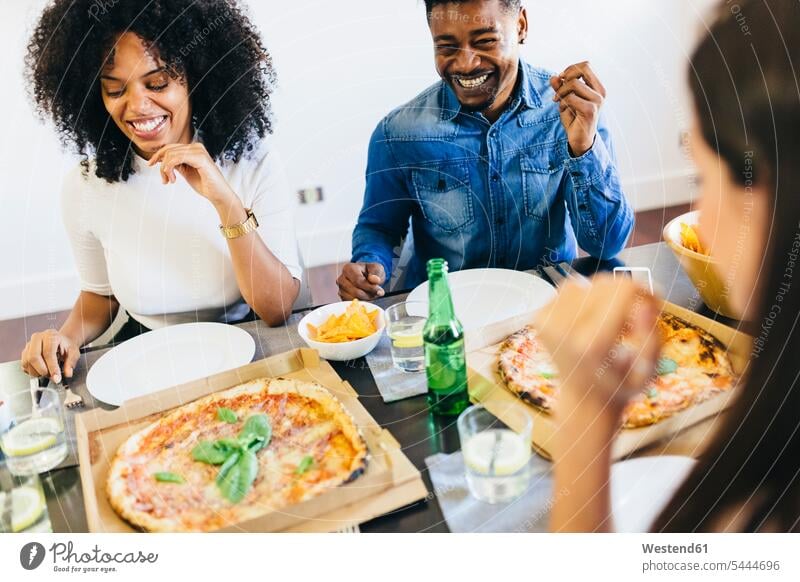 Gruppe von Freunden bei einer Pizza zu Hause Tisch Tische Pizzen essen essend Essen Food Food and Drink Lebensmittel Essen und Trinken Nahrungsmittel