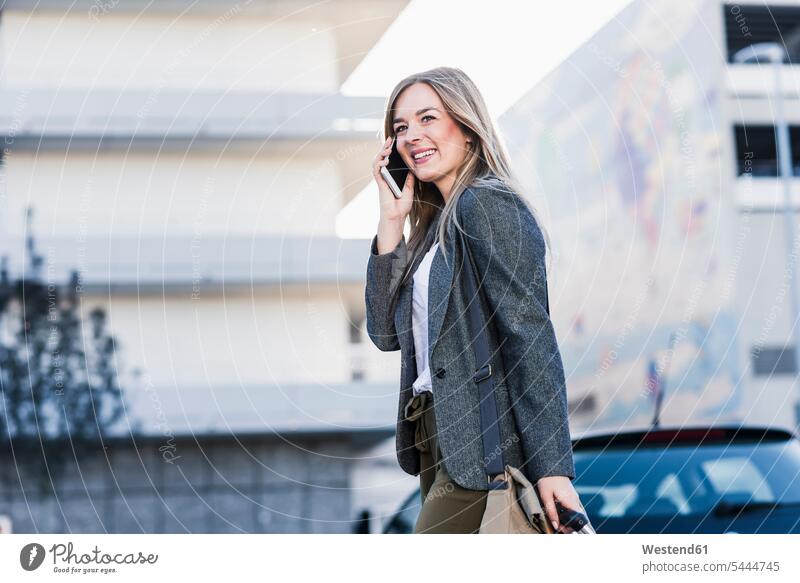 Glückliche junge Frau am Handy in der Stadt glücklich glücklich sein glücklichsein staedtisch städtisch telefonieren anrufen Anruf telephonieren Trolley