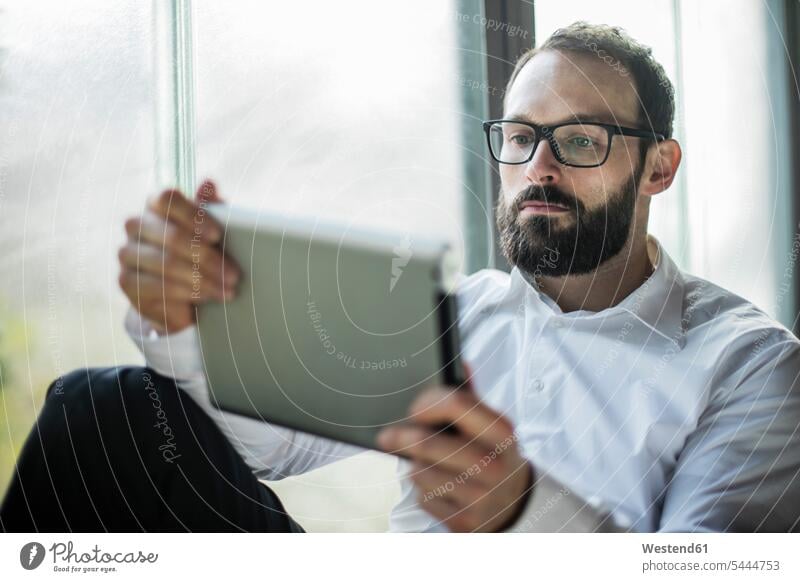 Geschäftsmann am Fenster sitzend, mit digitalem Tablett Tablet Computer Tablet-PC Tablet PC iPad Tablet-Computer zwanglos ungezwungen casual lässig leger