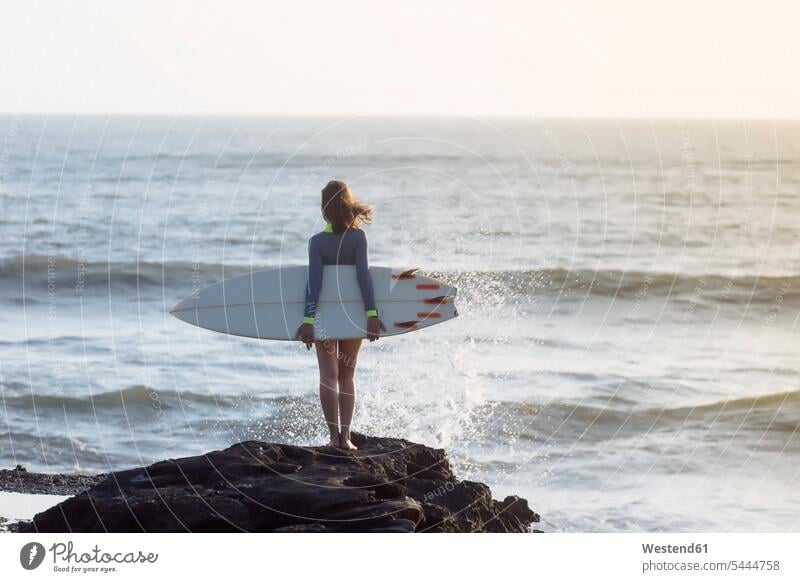 Indonesien, Bali, junge Frau mit Surfbrett tragen transportieren Meer Meere Surferin Wellenreiterinnen Surferinnen stehen stehend steht Freizeit Muße weiblich