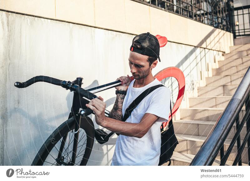 Junger Mann trägt unten ein Fixie-Rad Fahrrad Bikes Fahrräder Räder Männer männlich Raeder Erwachsener erwachsen Mensch Menschen Leute People Personen Europäer