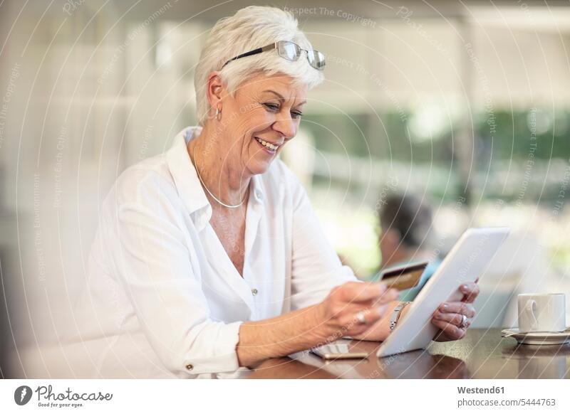 Ältere Frau kauft online mit Kreditkarte ein Shopping einkaufen shoppen Einkauf lächeln EC-Karte Kreditkarten Online Seniorin älter Seniorinnen alt bargeldlos