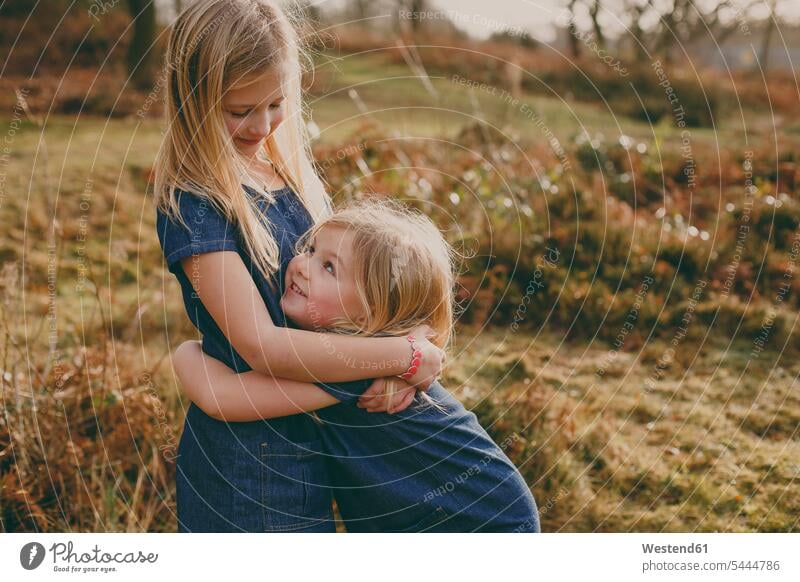 Zwei süße blonde Schwestern kuscheln im Freien Mädchen weiblich umarmen Umarmung Umarmungen Arm umlegen lächeln Kind Kinder Kids Mensch Menschen Leute People