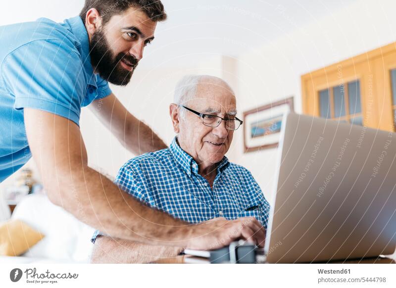 Erwachsener Enkel bringt seinem Großvater den Umgang mit dem Laptop bei Enkelsöhne Enkelsohn Opa Großpapa Großpapas Opas Opi Großväter Opis Notebook Laptops