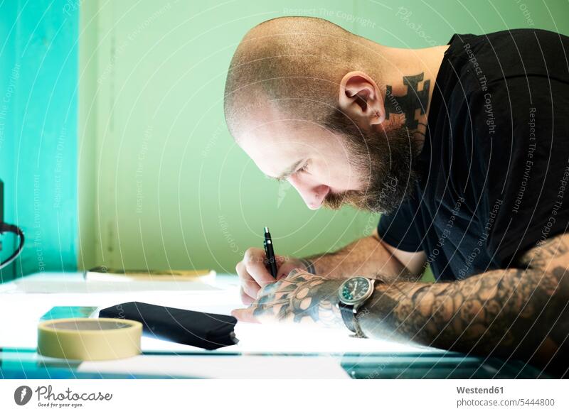 Tätowierer entwirft Motiv auf Leuchttisch im Studio Tattoo Tätowierungen Tatoos Taetowierung Tattoos Taetowierungen entwerfen Entwurf zeichnen Zeichnung