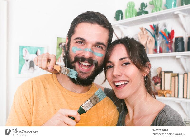 Porträt eines glücklichen jungen Paares mit Pinseln in der Hand malen Pärchen Partnerschaft lachen Glück glücklich sein glücklichsein Mensch Menschen Leute