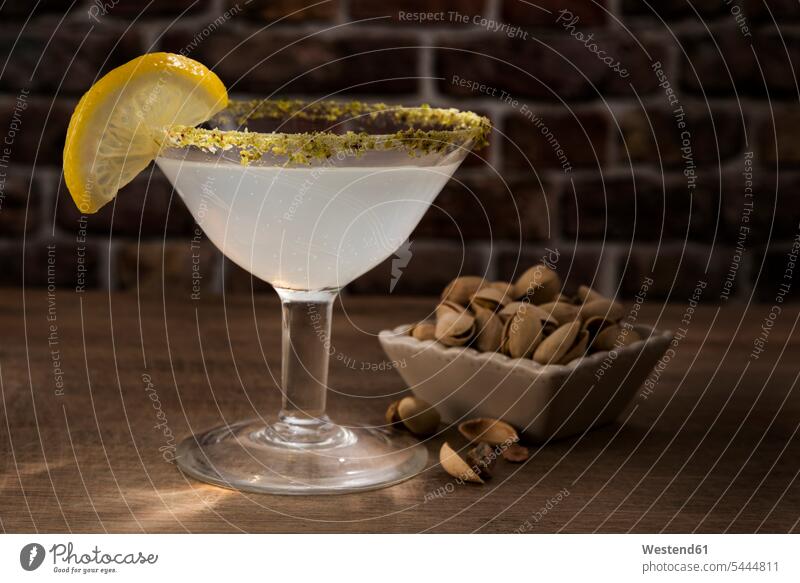 Glas Zitronentropfen-Martini mit Pistazie trinken Cocktailglas Cocktailgläser Cocktailglaeser Genuss genießen Genuß geniessen Lifestyle Lebensstil hölzern