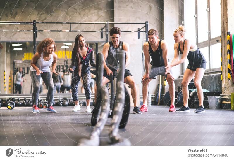 Gruppe junger fitter Menschen jubelt einem Mann zu, der mit Seilen in der Turnhalle trainiert trainieren Fitnesstraining Gesundheit gesund Sport Fitnessstudio