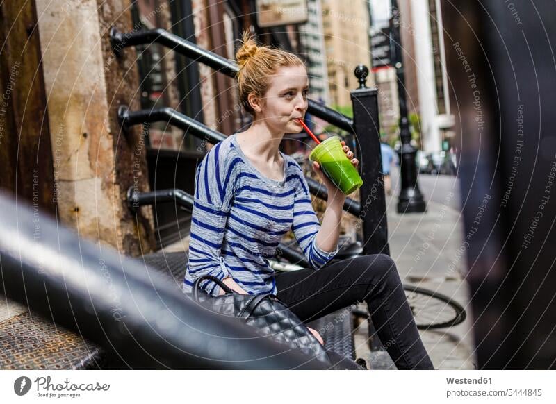 USA, New York City, Frau sitzt auf der Treppe und trinkt einen Smoothie in Manhattan weiblich Frauen trinken sitzen sitzend Smoothies Erwachsener erwachsen