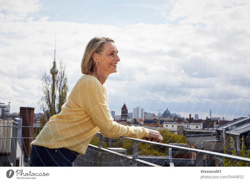 Lächelnde reife Frau auf Balkon mit Blick auf Aussicht Balkone Ausblick Ansicht Überblick lächeln weiblich Frauen Erwachsener erwachsen Mensch Menschen Leute