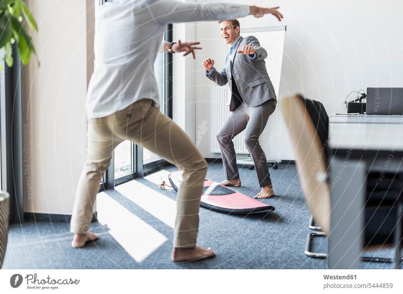 Zwei spielerische Kollegen mit Surfbrett im Büro Arbeitskollegen Spaß Spass Späße spassig Spässe spaßig Office Büros Surfbretter surfboard surfboards lachen