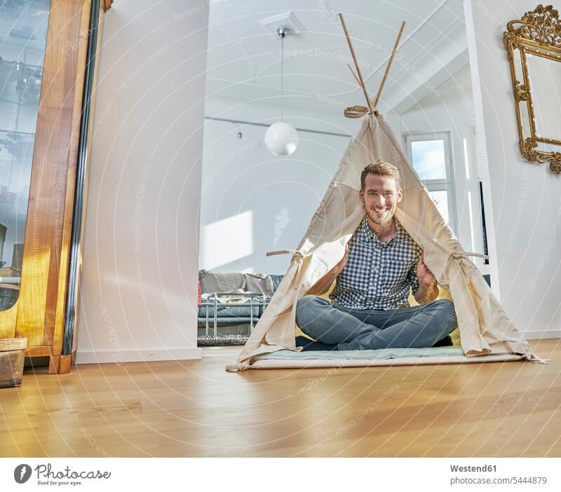 Lächelnder Mann sitzt in einem Tipi auf dem Boden lächeln Männer männlich Zelt Zelte Erwachsener erwachsen Mensch Menschen Leute People Personen sitzen sitzend
