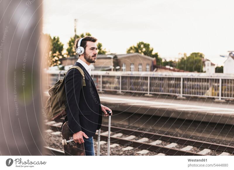 Junger Mann wartet auf dem Bahnsteig Männer männlich Koffer Zugbahnsteig Zugbahnsteige Bahnsteige reisen Travel verreisen Weg Reise Erwachsener erwachsen Mensch
