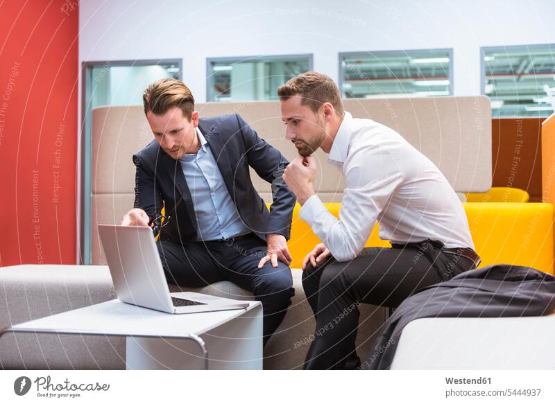 Geschäftsleute sitzen in der Gesprächsgrube und diskutieren vor dem Laptop Kollegen Arbeitskollegen Sitzecke sitzend sitzt Laptop benutzen Laptop benützen