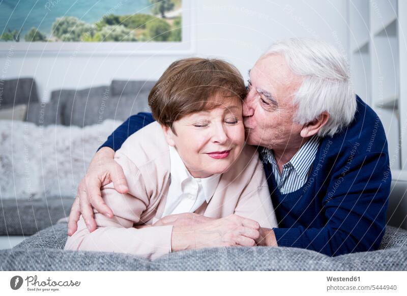 Älteres Paar liegt auf der Couch, umarmt und küsst sich küssen Küsse Kuss umarmen Umarmung Umarmungen Arm umlegen Pärchen Paare Partnerschaft Sofa Couches Liege