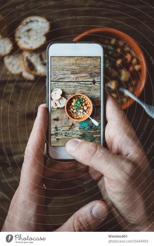 Menschenhand beim Fotografieren einer mediterranen Suppe in einer Schüssel, Nahaufnahme Eintopf Smartphone iPhone Smartphones fotografieren Hand Hände Mann