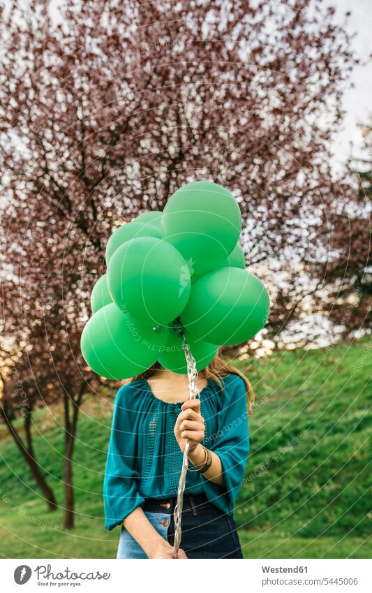 Junge Frau versteckt sich hinter grünen Luftballons weiblich Frauen Ballons Luftballone Erwachsener erwachsen Mensch Menschen Leute People Personen verstecken