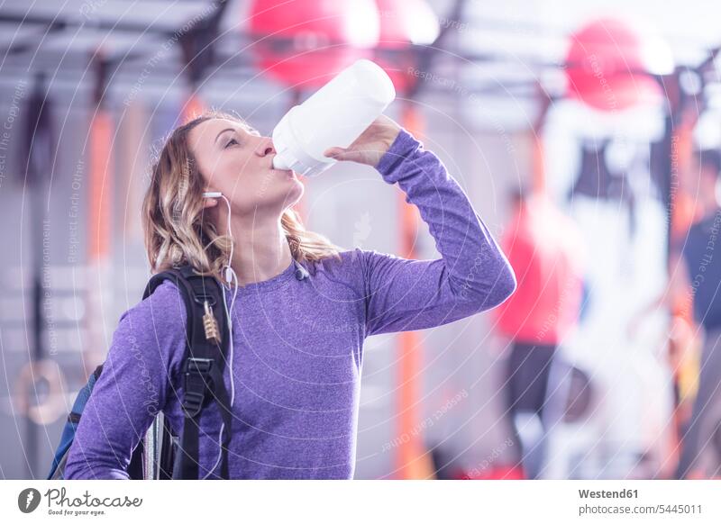Junge Frau macht eine Erfrischungspause im Fitnessstudio Pause Fitnessclubs Fitnessstudios Turnhalle weiblich Frauen trinken trainieren fit Gesundheit gesund